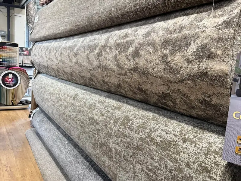 Grey and oatmeal carpet rolls displayed in the Farrells showroom.