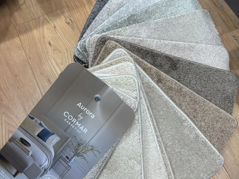 A fan of carpet samples in cream, grey and natural tones at Farrells.